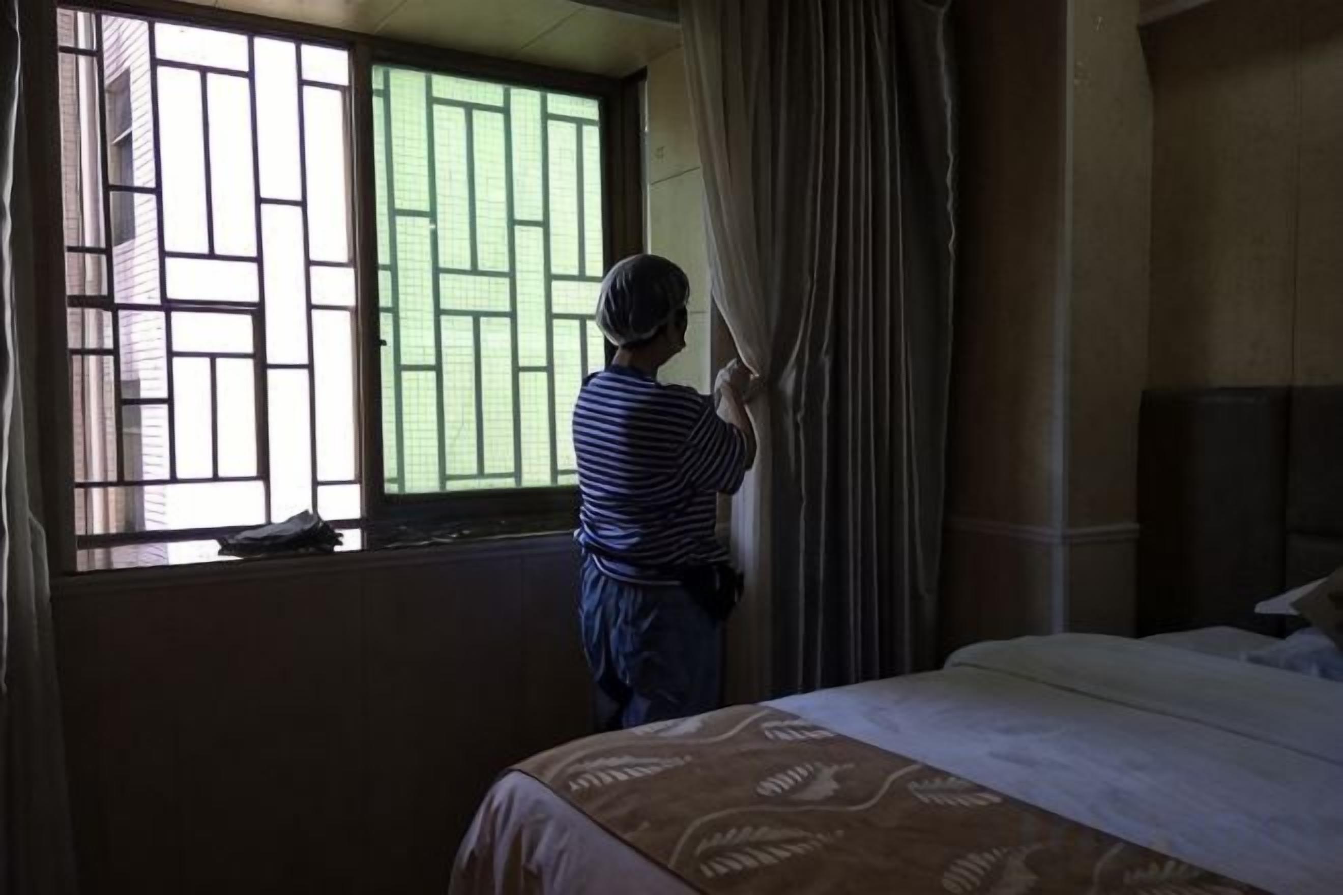 Ein Zimmer mit einem Bett, einem Vorhangfenster und Blick nach außen.