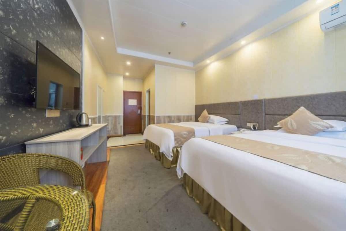 Habitación de hotel con dos camas, una zona de estar pequeña, un espejo y una kitchenette.