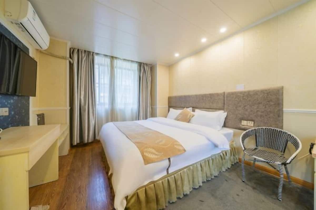 Una habitación de hotel con una cama, una silla, un escritorio y un equipo de aire acondicionado.