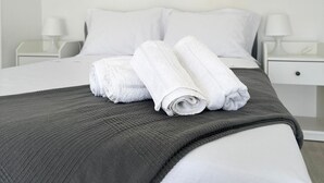 A neatly made bed with white linens and a grey blanket, two bedside tables with lamps, and a white headboard. - Ceazltina Lima Group Guest House (Agualva-Cacém)