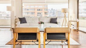 Ein modernes Wohnzimmer mit einer Couch, zwei Ledersesseln, einem Couchtisch und einer Stehlampe.