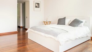 Ein modernes Schlafzimmer mit einem großen Bett, einem Nachttisch und einem gerahmten Bild an der Wand.
