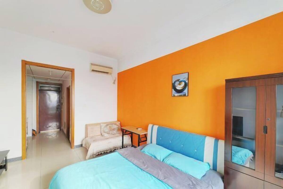 Een slaapkamer met een bed, een slaapbank, een kledingkast en een deur naar een andere kamer.