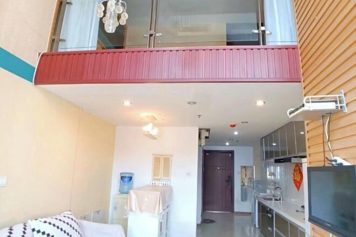 Een modern appartement met balkon, een keuken met televisie en een eethoek.