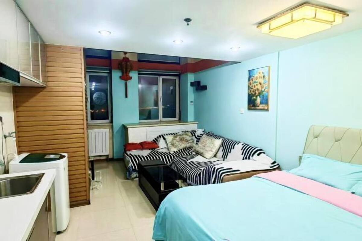Een kleine slaapkamer met een bed, een slaapbank, een tafeltje en een raam.