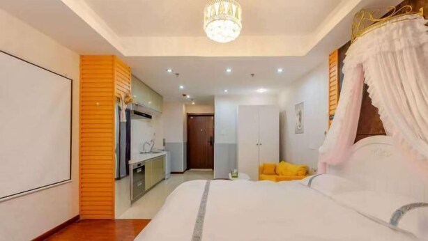 A bedroom with a bed, a chandelier, a wardrobe, and a desk with a chair. - Yi Ju Hotel Apartments (Tianjin)