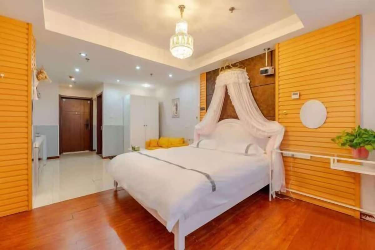 Een slaapkamer met een hemelbed, houten lambrisering, een plafondlamp en een kleine plant.