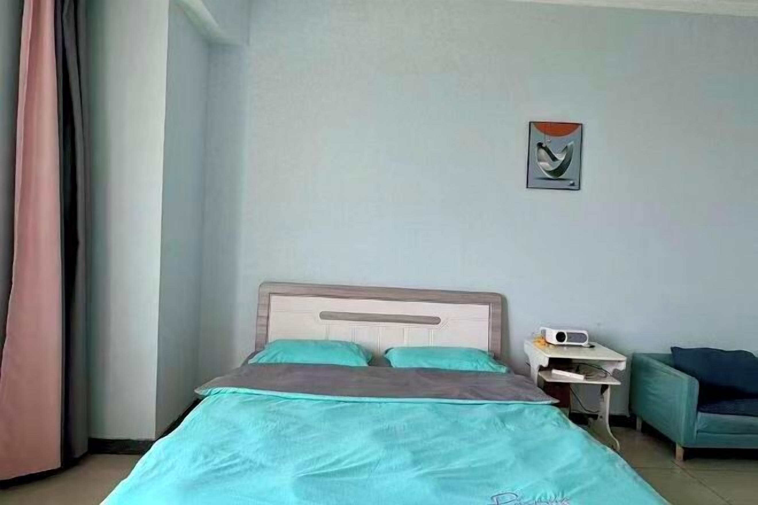 A hotel room with a bed, a nightstand, a chair, and a painting on the wall.