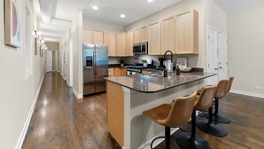 Una cocina moderna con armarios de madera, electrodomésticos de acero inoxidable y una isla central con taburetes de bar.