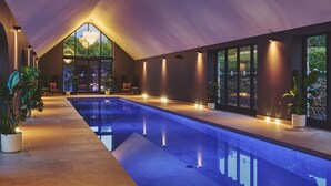 Piscina interior moderna com teto inclinado e grandes janelas.