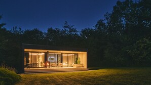 Uma casa moderna e bem iluminada com fachada de vidro, lareira e área de estar externa.