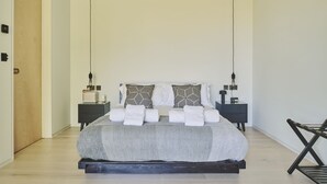 Quarto moderno com uma cama grande, duas mesas de cabeceira e uma cadeira.