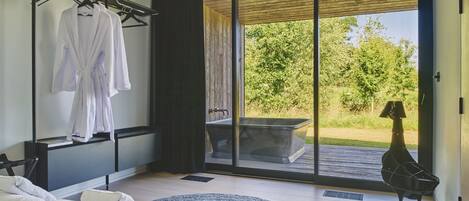 A modern bathroom with a large sliding glass door leading to a deck, a bathtub, and a shower area.