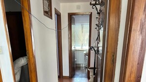 Un pasillo con suelo de baldosas, una planta en maceta y un marco de puerta de madera.