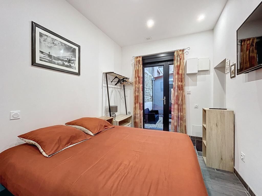 A bedroom with a large bed, a wardrobe, a mirror, and a framed picture on the wall.