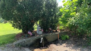 A garden with a statue, American flags, and a bird feeder. - Rustic cottage by the mighty Elk! (Girard)