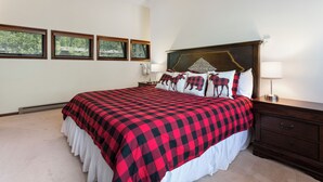 A bedroom with a large bed, a nightstand, a lamp, and three windows. - Spacious Townhome on Shuttle Route, Just Minutes to Vail Resort! (Vail)