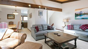 A spacious living room with a grey sofa, a wooden coffee table, and a dining area with a table and chairs. - Spacious Townhome on Shuttle Route, Just Minutes to Vail Resort! (Vail)