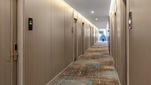 Un pasillo largo y estrecho con puertas a ambos lados, cada una con una pequeña placa encima.
