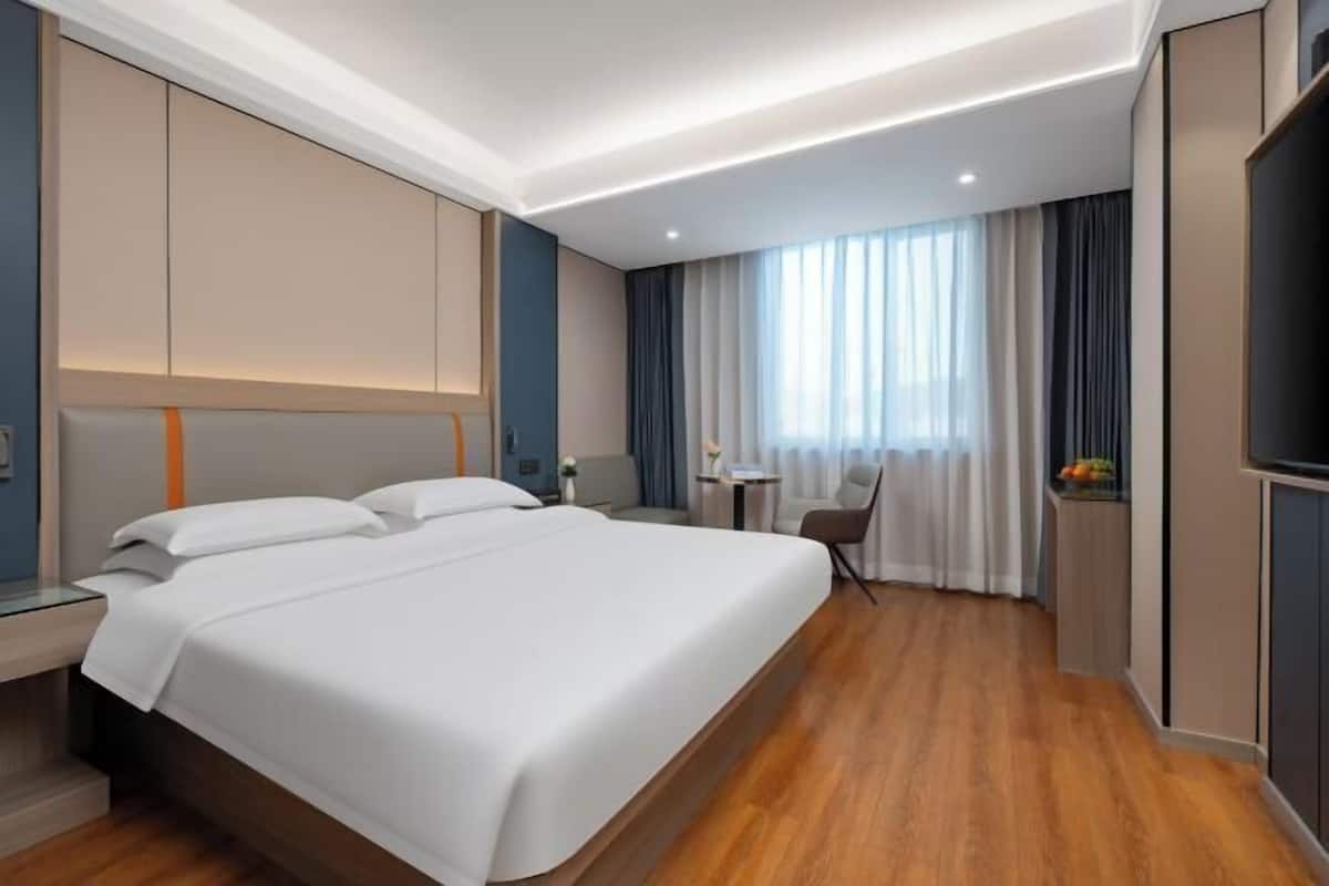 Een moderne hotelkamer met een groot bed, een bureau en een televisie.