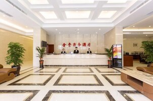 Zona de recepción de hotel con suelo de mármol, mostrador de recepción y un amplio ventanal.