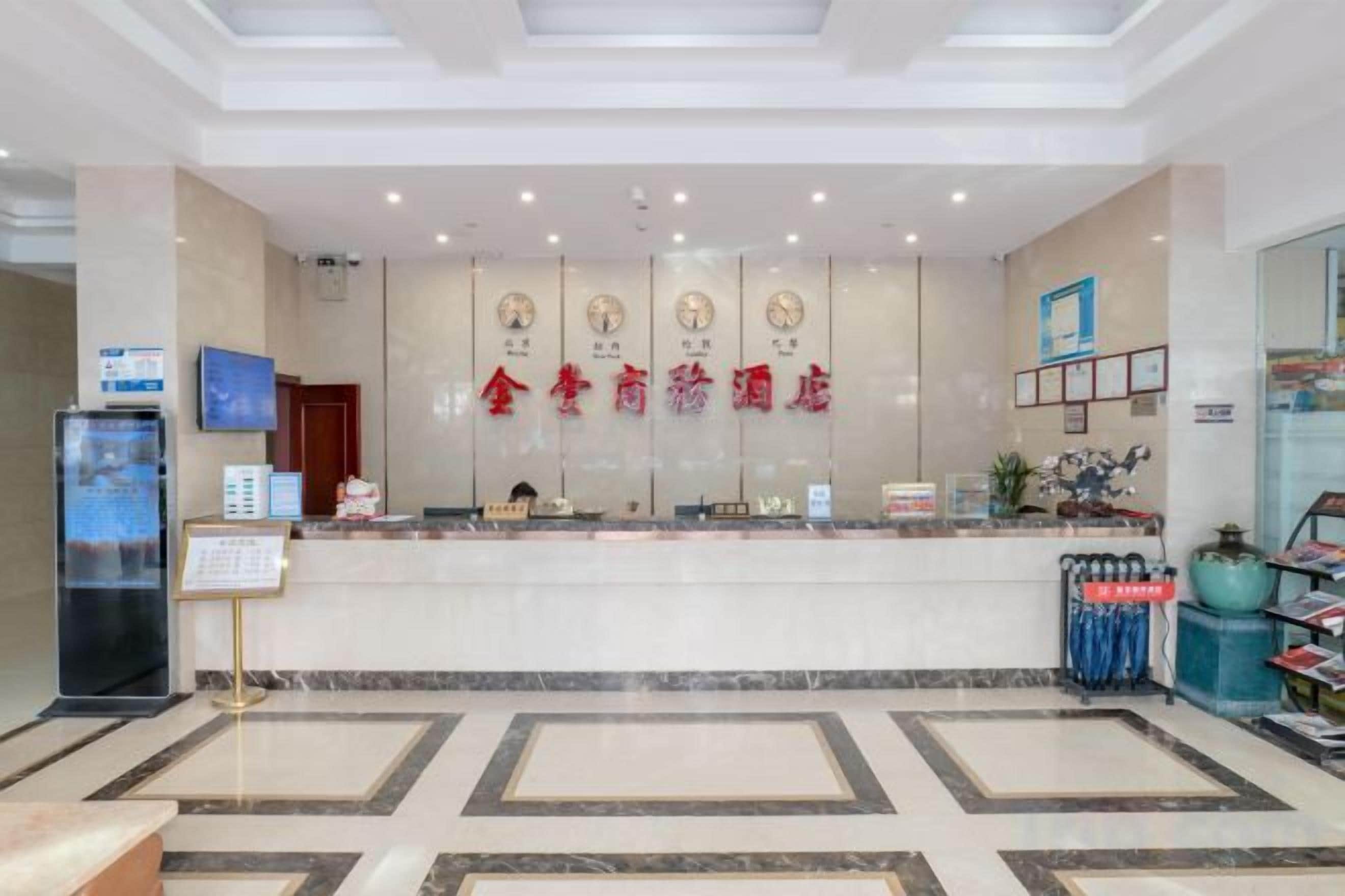 A hotel reception area with a marble floor, a reception desk, and a wall with clocks and a sign.