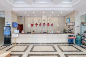 A hotel reception area with a marble floor, a reception desk, and a wall with clocks and a sign. - Wenzhou Jinfeng Business Hotel (Yongjia)