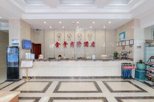 A hotel reception area with a marble floor, a reception desk, and a wall with clocks and a sign.