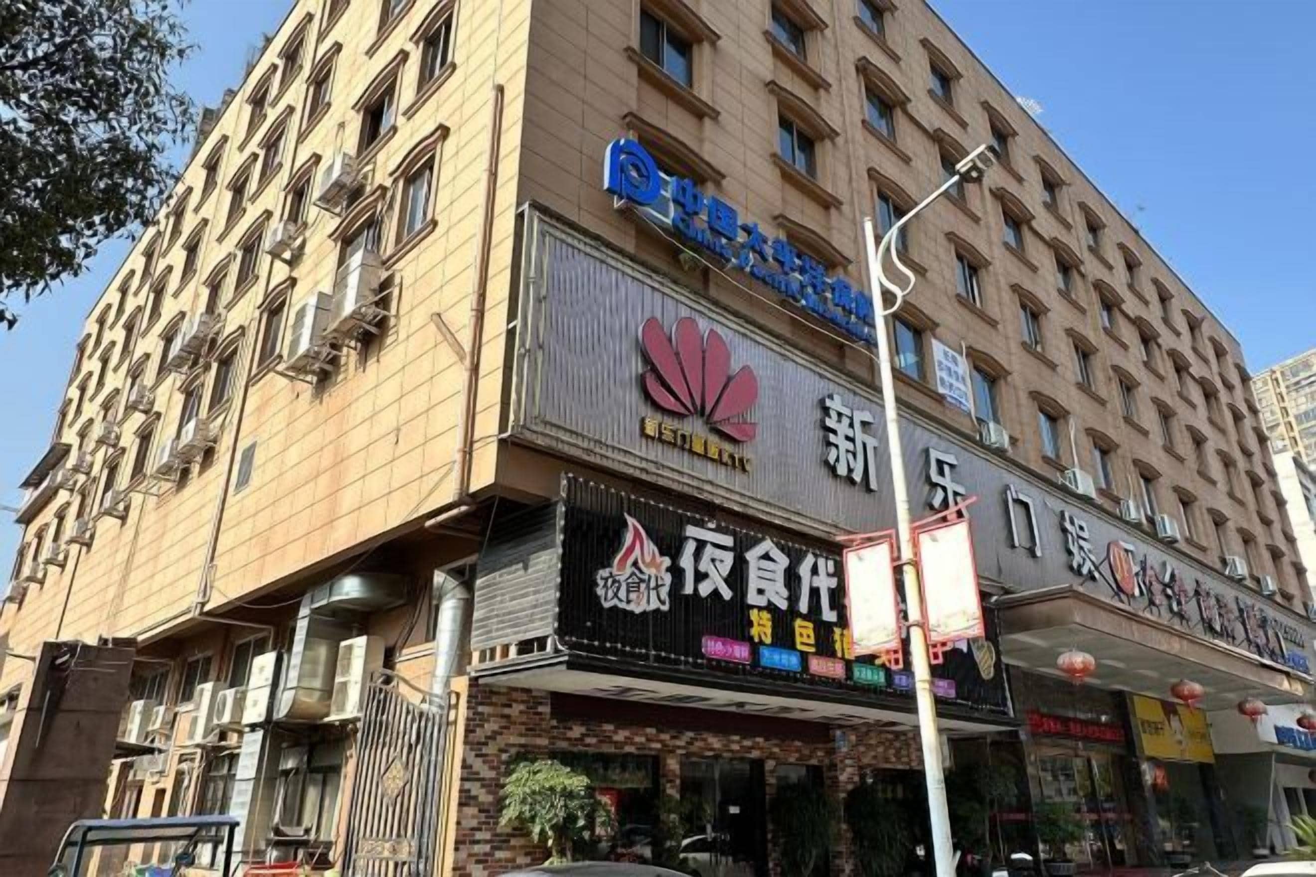 A multi-story building with commercial establishments on the ground floor, including a restaurant and a convenience store.