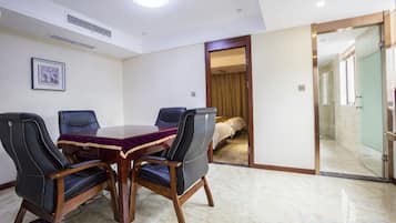 A conference room with a round table, four chairs, and a glass door leading to a bedroom.