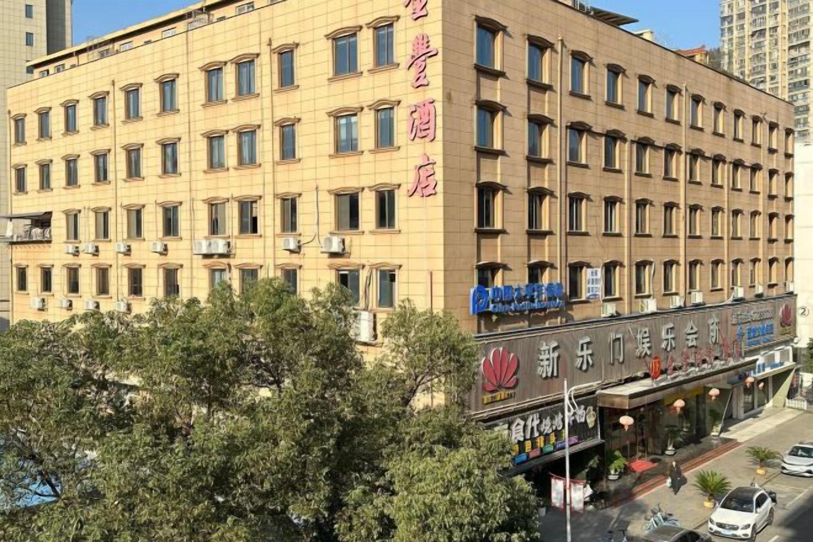 Un hotel a più piani con facciata uniforme, numerose finestre e una zona commerciale a livello strada con insegne.