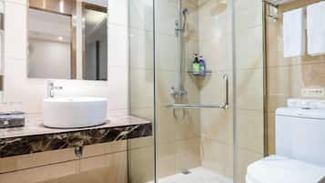 Un baño moderno con ducha de vidrio, un lavamanos blanco y un inodoro.