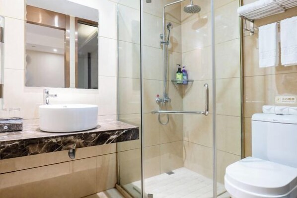 Een moderne badkamer met een douche met glazen wand, een witte wastafel en een toilet.