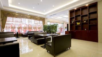 A hotel lobby with seating areas, a reception desk, and a large plant.