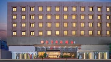 A multi-story hotel with a row of uniformly lit windows and a prominent entrance with signage.