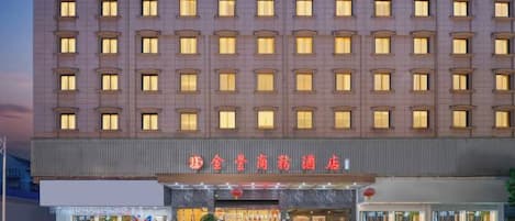 A multi-story hotel with a row of uniformly lit windows and a prominent entrance with signage.
