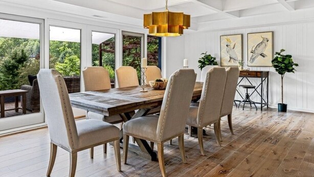 Een eetruimte met een houten tafel, zes stoelen en een hanglamp.