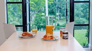 Una tavola per la colazione con una caraffa di succo d'arancia, due piatti di cibo, un vasetto di marmellata e un bicchiere di succo d'arancia.