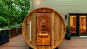 Une structure de sauna en bois, dotée d’une porte, d’un panneau de commande et d’un banc à l’intérieur.