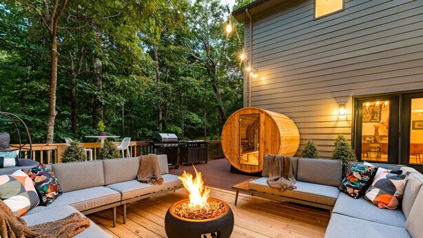 Un espace extérieur accueillant avec un foyer, une terrasse en bois et un grand tonneau en bois.