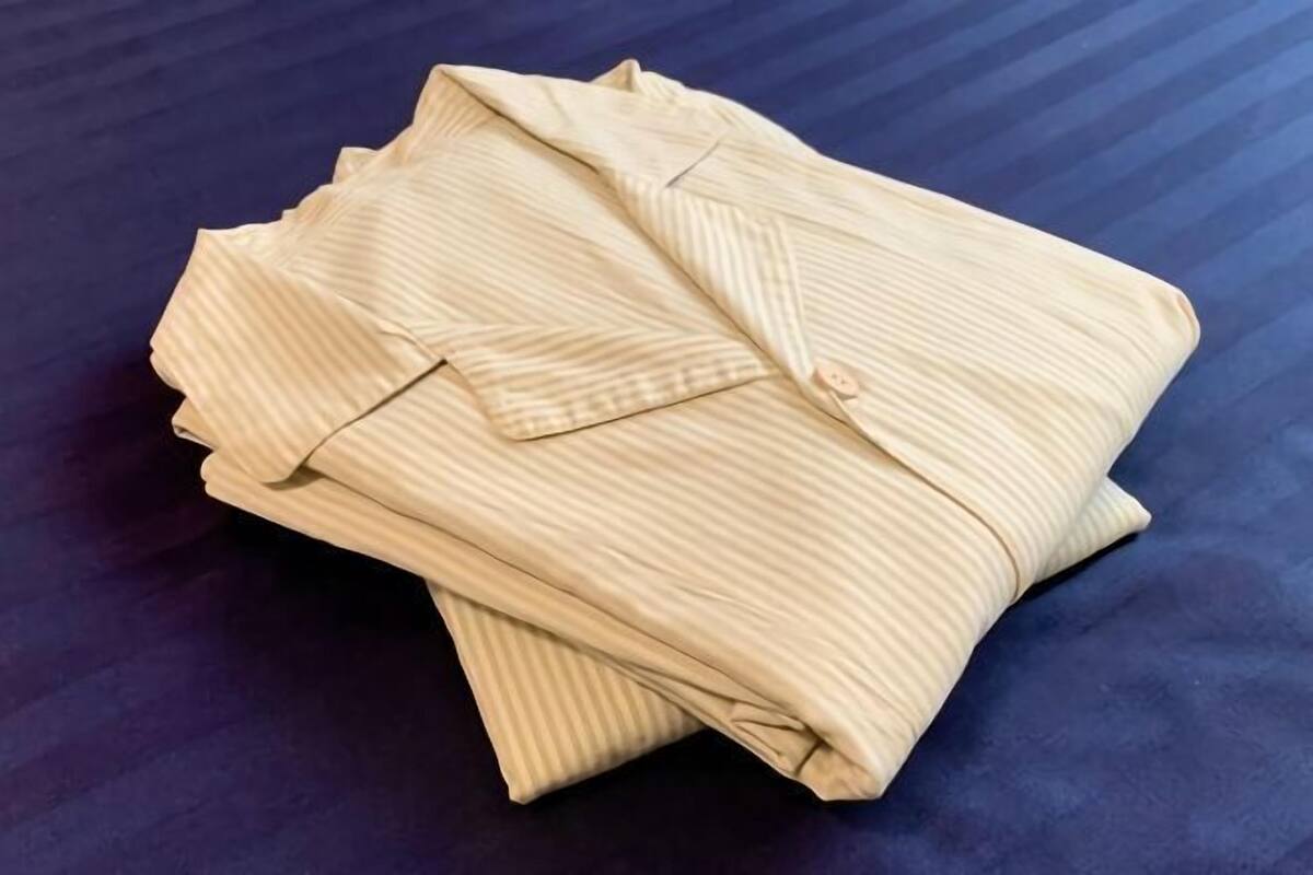 A neatly folded light-colored striped shirt on a dark blue surface.