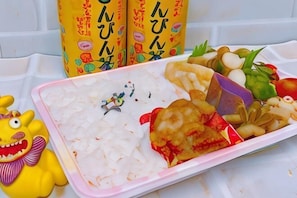 A tray with various food items, a toy, and two bottles with Japanese text. - Hotel Airway (Naha)