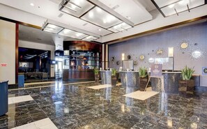 Un vestíbulo moderno con suelo de mármol, mostrador de recepción y zona de bar.