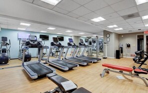 Un gimnasio con cintas de correr, una prensa de banca y diversas máquinas de ejercicio.