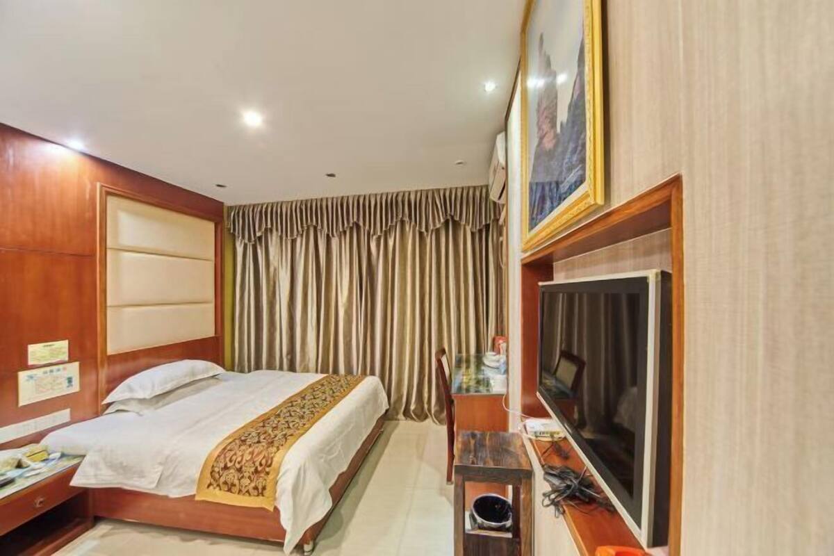 Une chambre d’hôtel avec un lit, un bureau, une télévision et des rideaux.