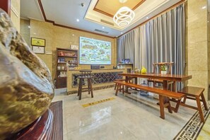 A hotel lobby with a reception desk, seating area, and a large screen displaying a map.