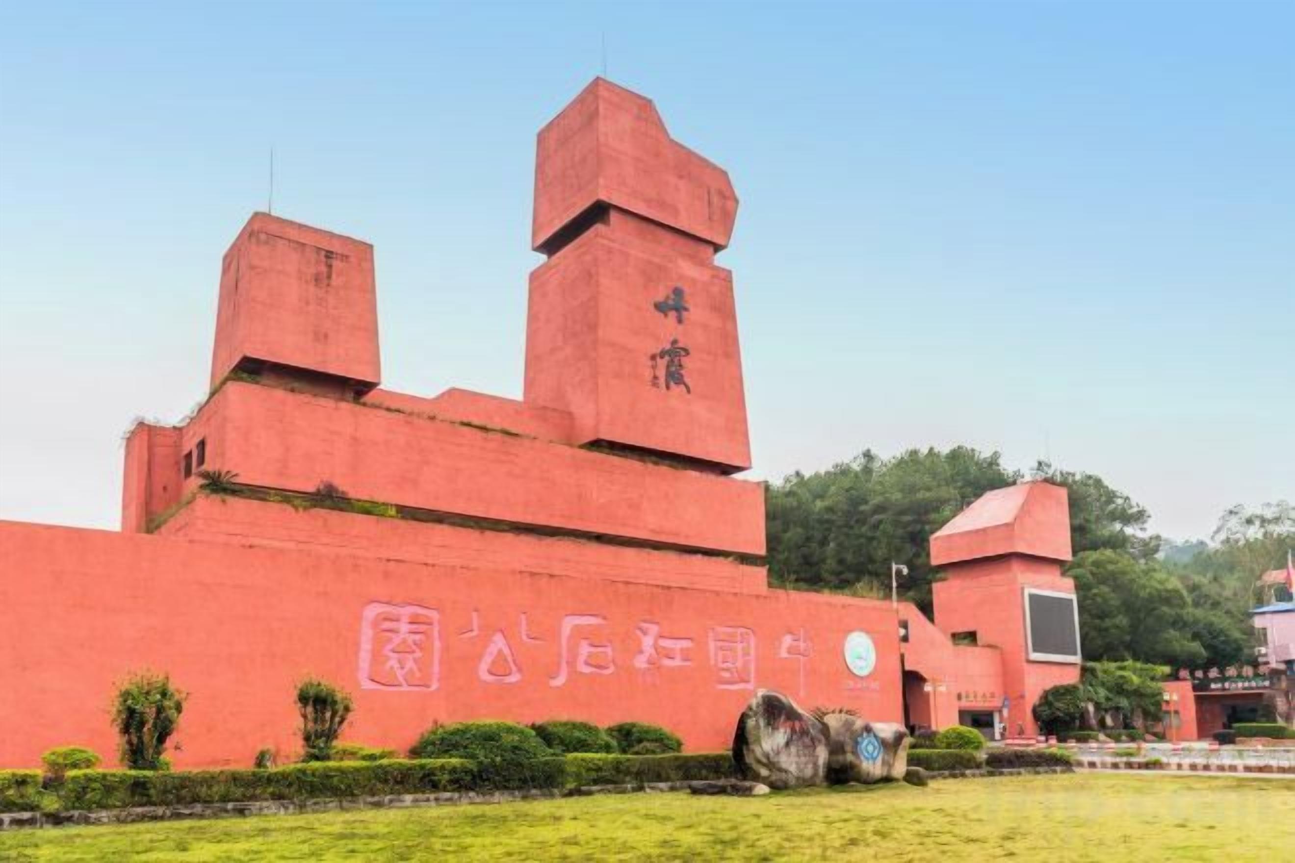 Un edificio rojo con un diseño arquitectónico singular, que presenta una torre destacada y un gran emblema circular en la fachada.