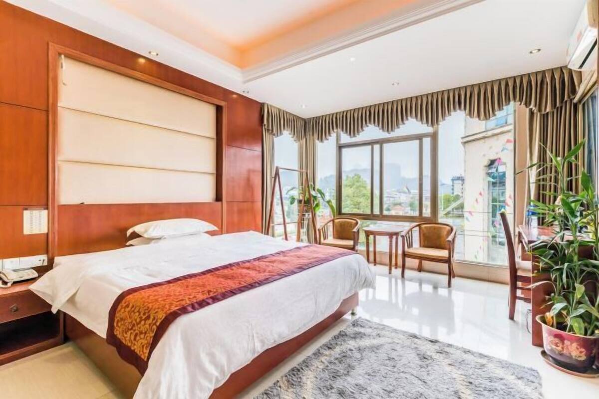 Une chambre d’hôtel avec un grand lit, un bureau, une chaise et une vue sur la ville.