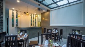 A restaurant with wooden tables and chairs, a glass ceiling, and a projection screen on the wall. - The Tito Suite Residence (Siem Reap)