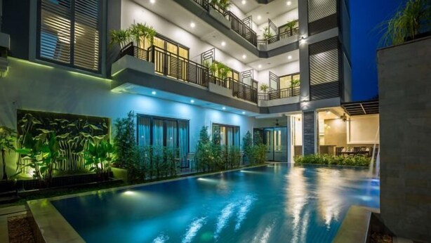 A modern hotel with a swimming pool, balconies, and indoor plants. - The Tito Suite Residence (Siem Reap)